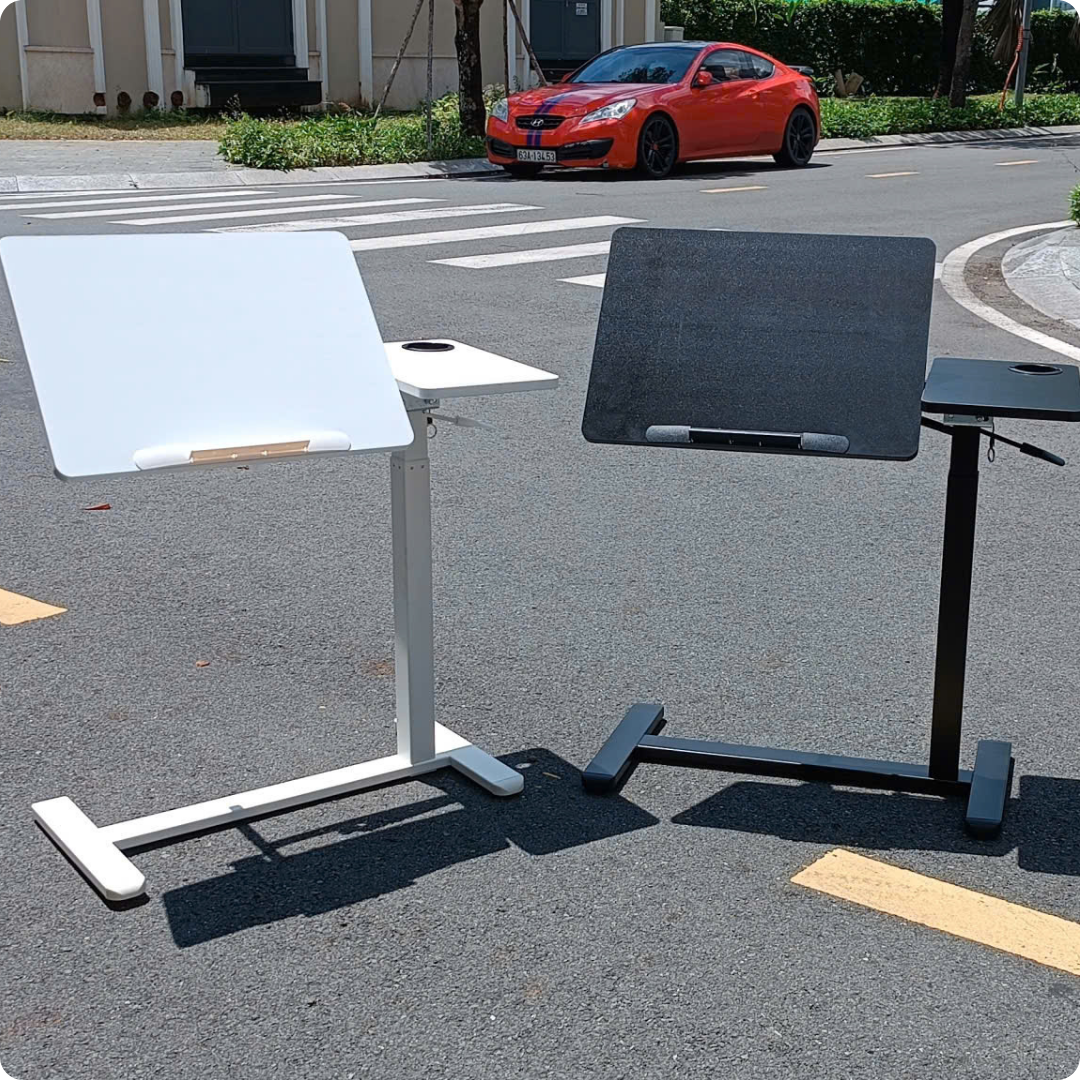 Bàn nâng hạ cạnh giường ngủ tại nhà, cạnh ghế sofa, mặt bàn có khả năng xếp gọn khi không dùng.