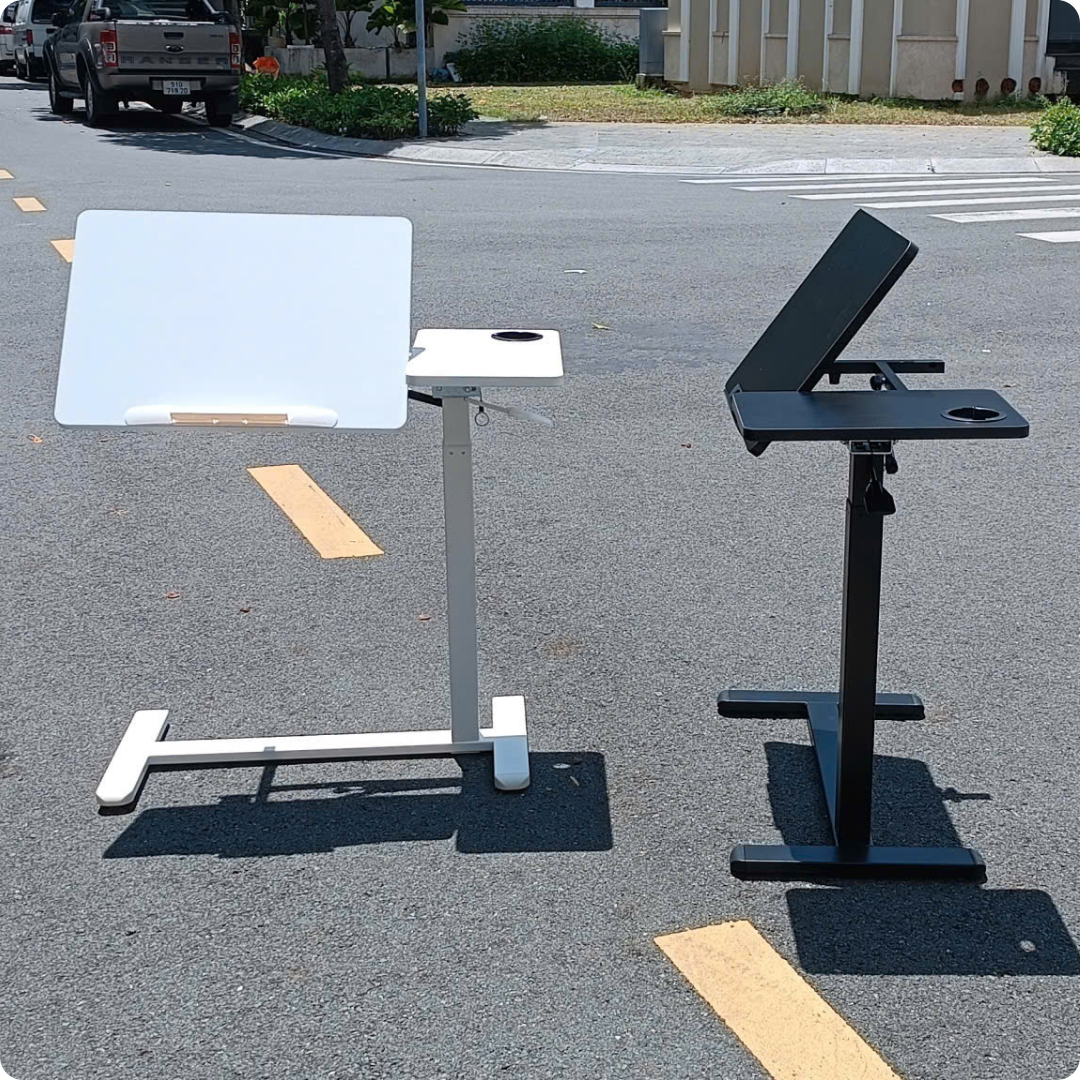 Bàn nâng hạ cạnh giường ngủ tại nhà, cạnh ghế sofa, mặt bàn có khả năng xếp gọn khi không dùng.